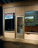 Color photograph of the outside of a motel lobby at night.