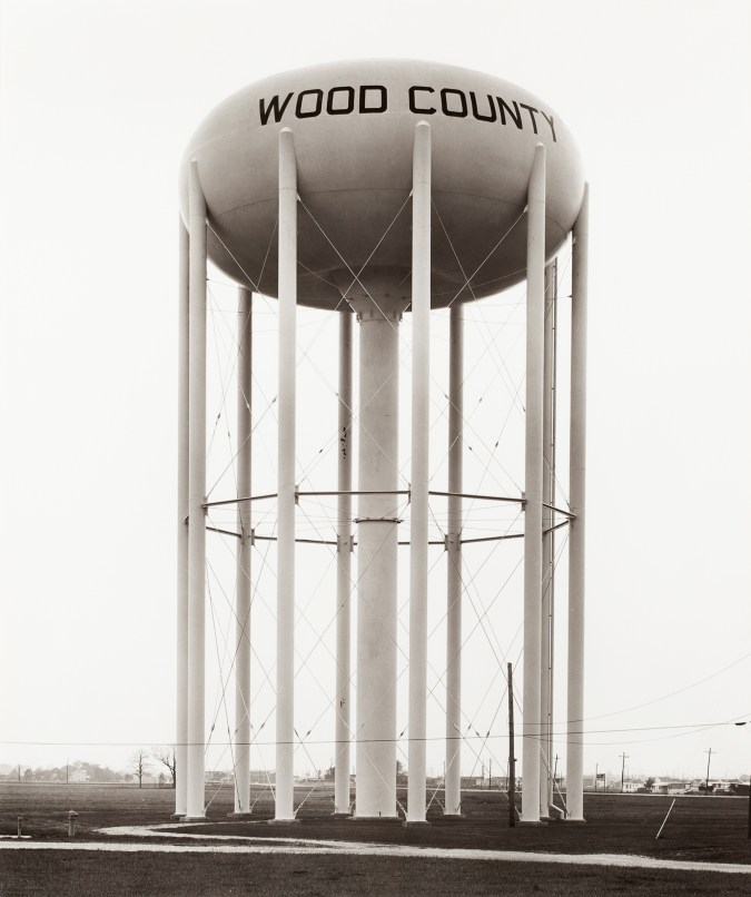 Black and white photograph of a water tower in a grass field