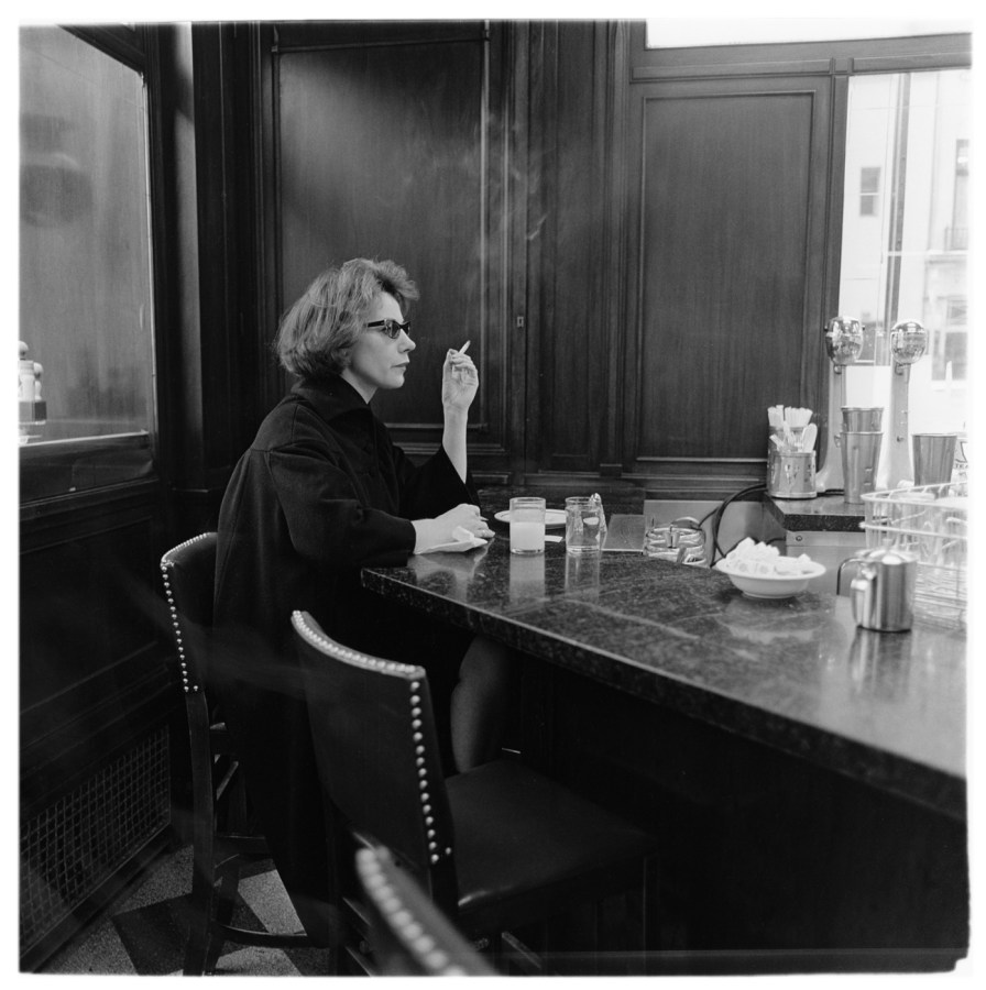 Black-and-white photograph of a woman sitting alone at a counter