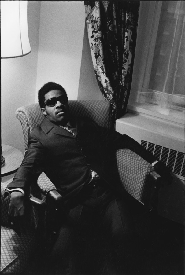 Black and white photograph of seated male figure in sunglasses and suit
