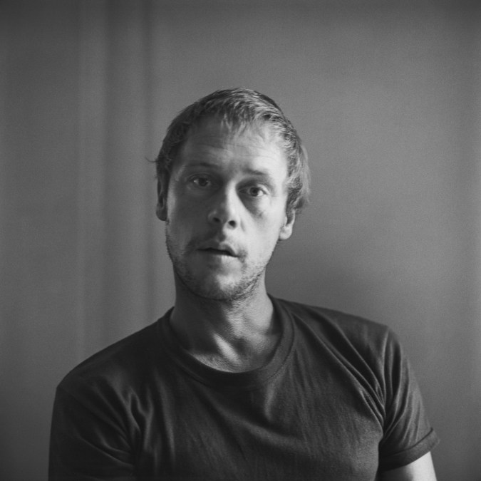 Black and white photograph of a slightly blurred male figure looking at the viewer