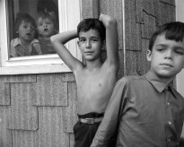 Children gathered around a window looking out or standing next to the building outside