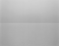 Black and white photograph of a calm waterscape under a flat grey sky