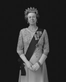Black and white photograph of a wax figure of an older woman dressed in a crown and sash